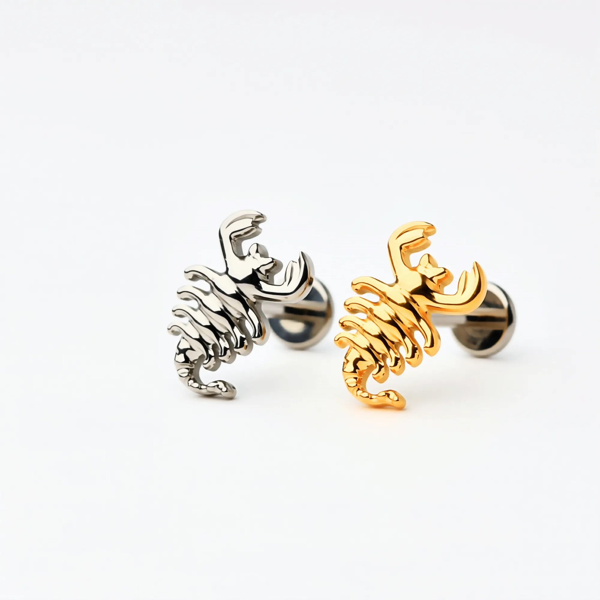 Titanium Scorpion Curve flat back stud earrings in natural titanium and gold, featuring a curved textured design. Front view showing implant-grade titanium push-in posts and hypoallergenic flat back construction.