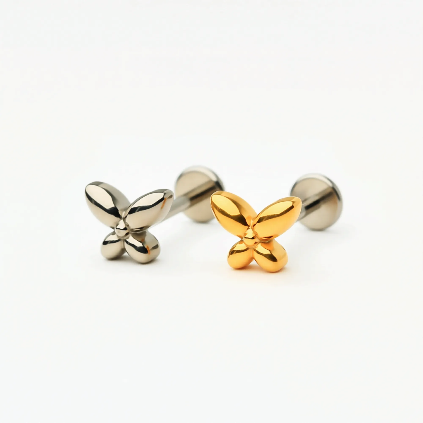 Titanium Petite Butterfly flat back stud earrings in natural titanium and gold, featuring a delicate butterfly design. Front view showing hypoallergenic implant-grade titanium push-in posts and flat back style.