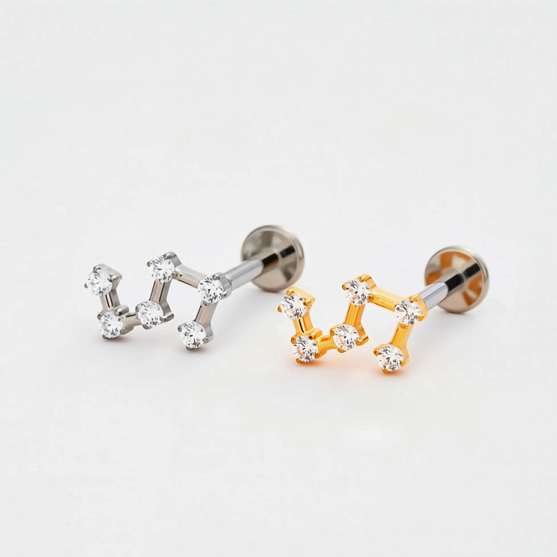 Titanium Stellar Steps internally threaded flat back stud earrings in natural titanium and gold, featuring a multi-stone constellation-inspired design. Front view of hypoallergenic implant-grade titanium studs.