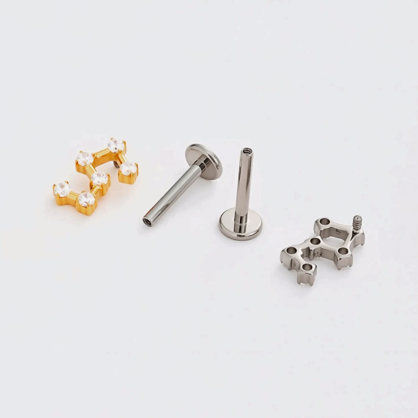 Disassembled Titanium Stellar Steps internally threaded flat back stud earring showing the gold and natural titanium constellation-style tops, implant-grade titanium post, visible internal threading, and smooth flat back base.