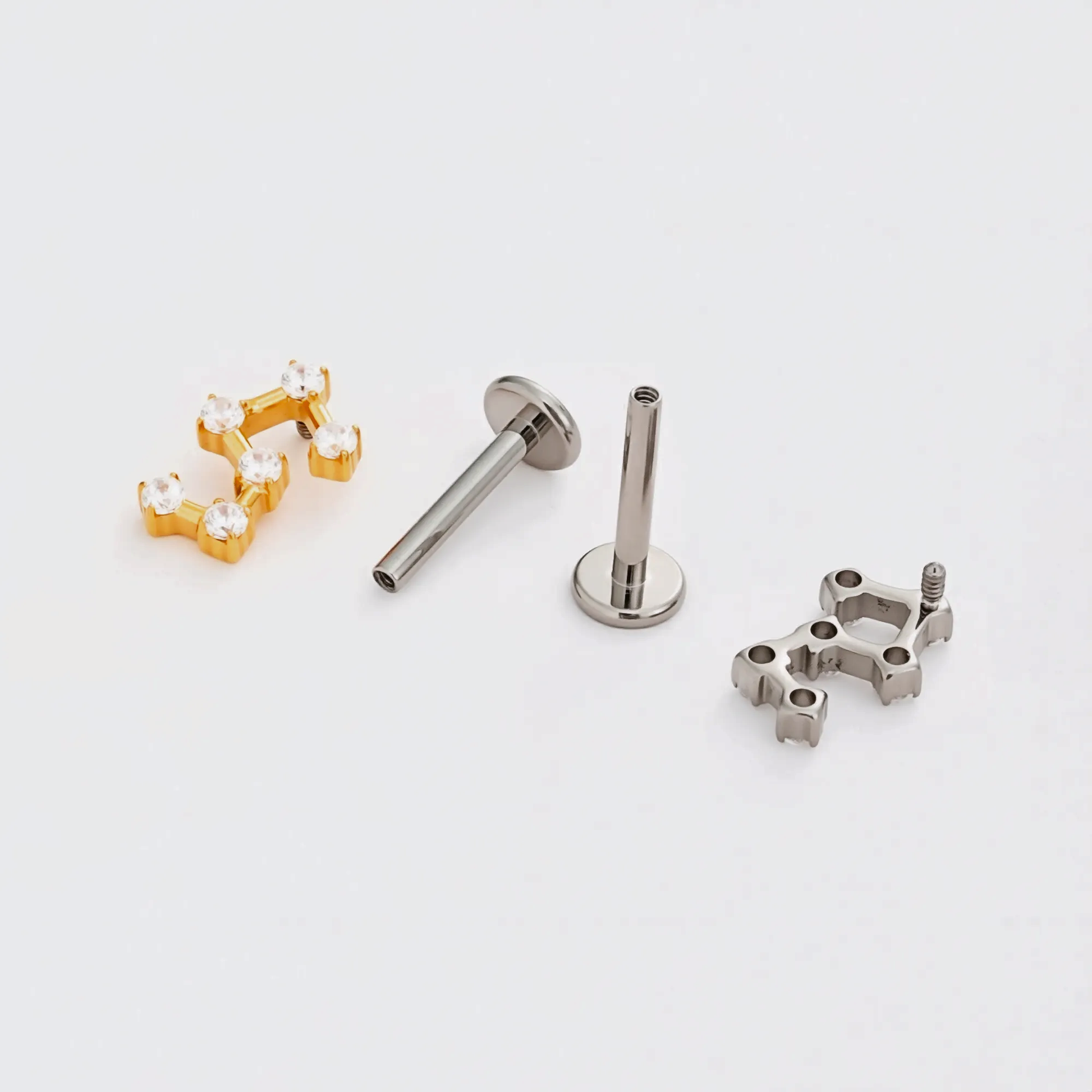 Disassembled Titanium Stellar Steps internally threaded flat back stud earring showing the gold and natural titanium constellation-style tops, implant-grade titanium post, visible internal threading, and smooth flat back base.