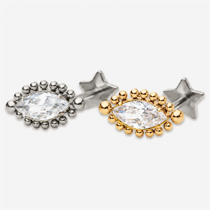 Celestial Eye flat back stud earrings in titanium and gold, with a marquise-cut clear stone and beaded setting.