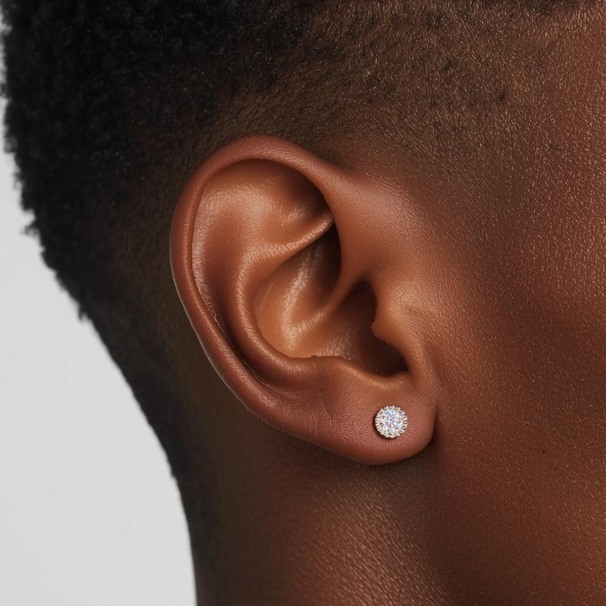 Model wearing the Titanium Crown Spark internally threaded flat back stud earring with a round crystal and crown-style setting, showing fit and sparkle on the ear.