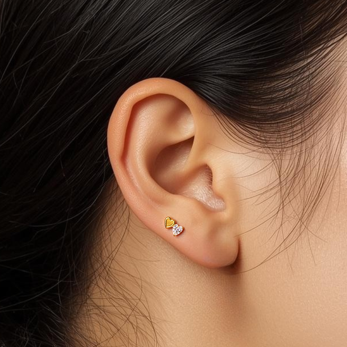 Close-up of model wearing the gold Titanium Duo Heart internally threaded flat back stud earring, highlighting the crystal and metal heart design and flat back comfort.