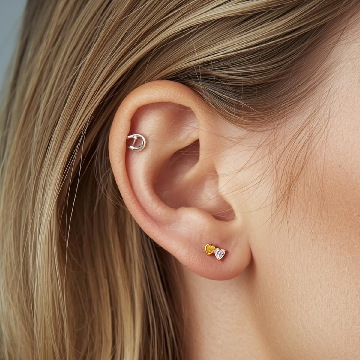 Model wearing the Titanium Duo Heart internally threaded flat back stud earring in natural titanium, showing the double-heart design and comfortable flat back fit.