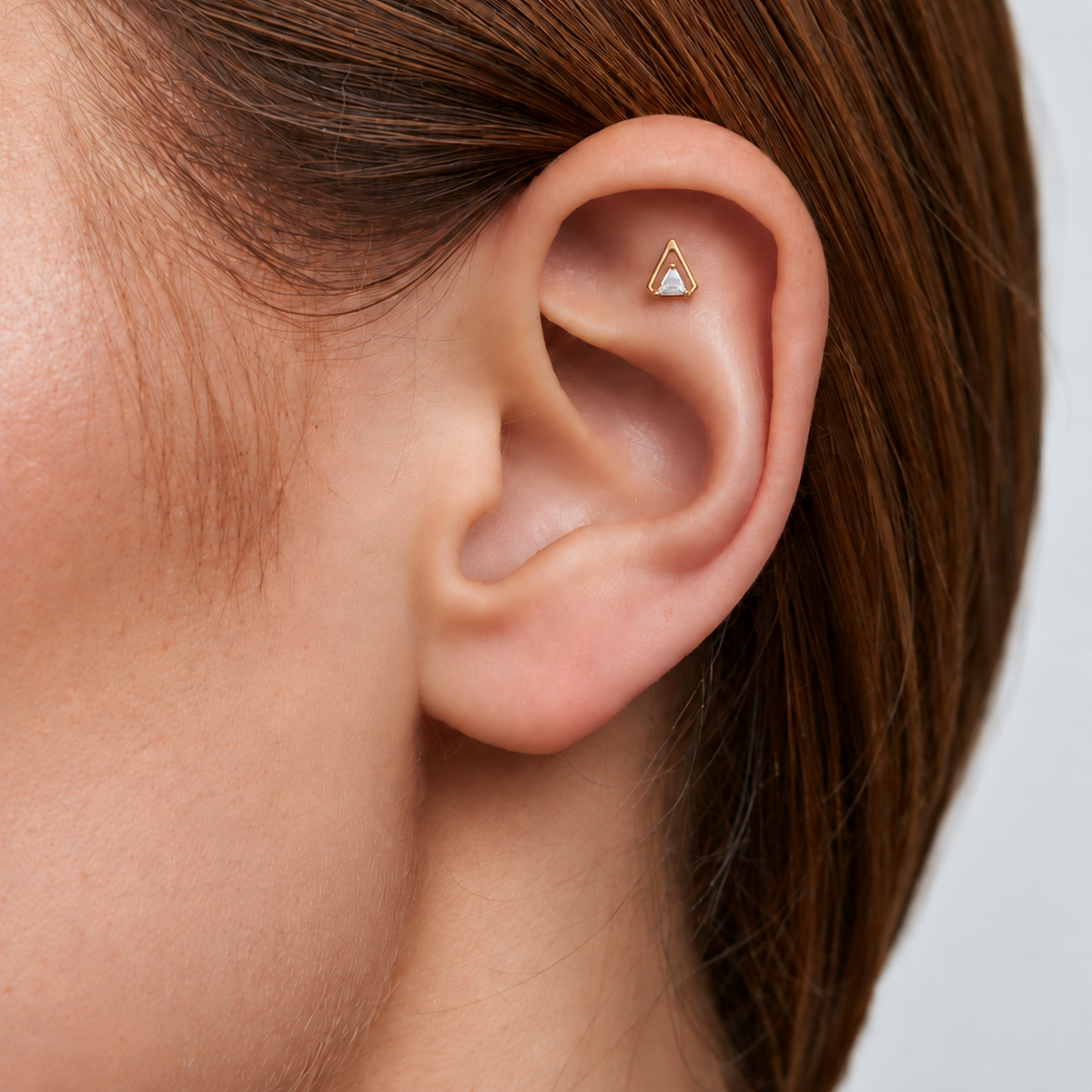 Nova Triangle gold-plated titanium earring worn on the flat piercing