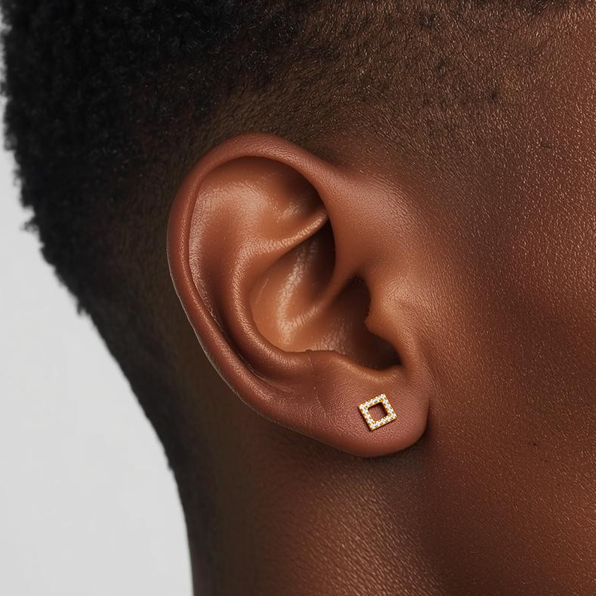 Model wearing the Spark Frame internally threaded titanium flat back stud earring, showing the square crystal frame and the smooth implant-grade titanium star flat back post.