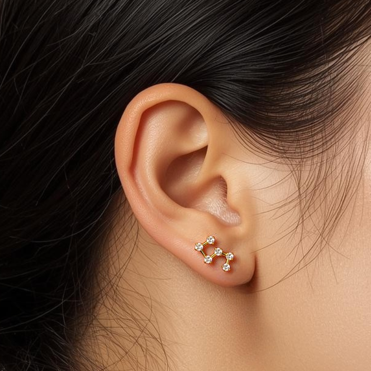Model wearing the Titanium Stellar Steps internally threaded flat back stud earring, showing the constellation-style design and comfortable flat back fit.
