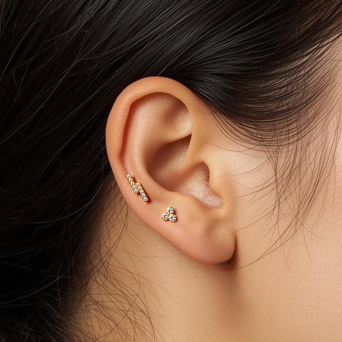 Close-up of model wearing the gold Titanium Twin Bar internally threaded flat back stud earring, highlighting the sleek twin-bar design and implant-grade titanium flat back.